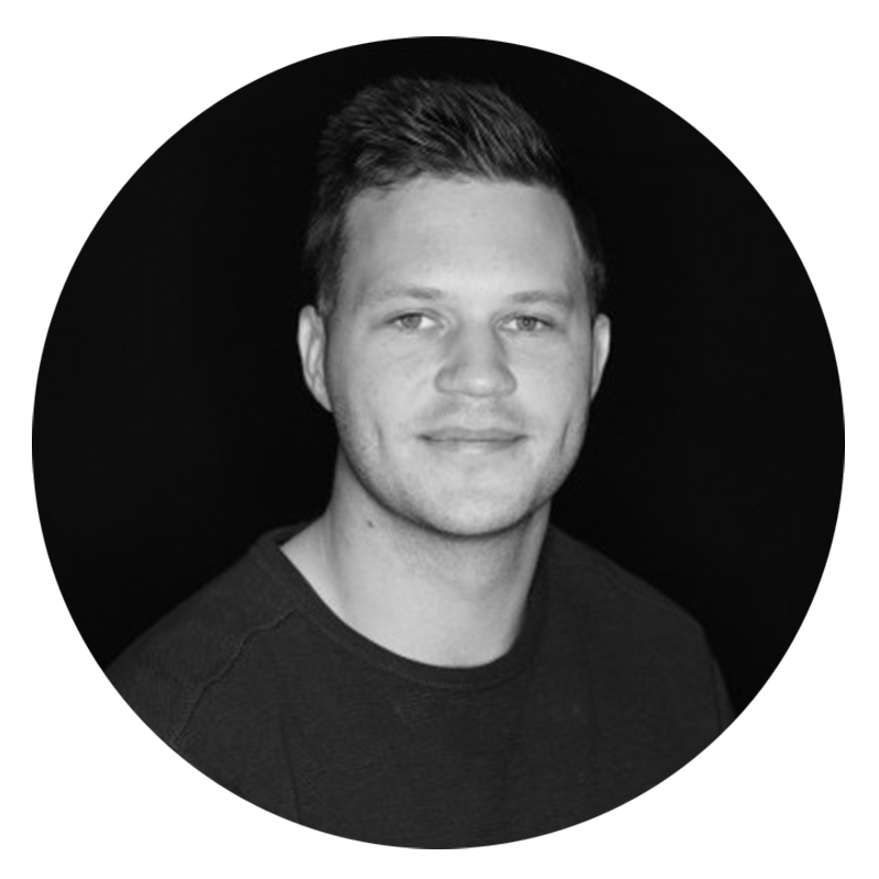 Smiling man with short hair, black background.